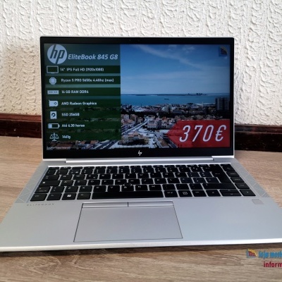 Computador portátil HP EliteBook 845 G8 prata com teclado preto e ecrã ligado sobre mesa de madeira clara com parede branca atrás