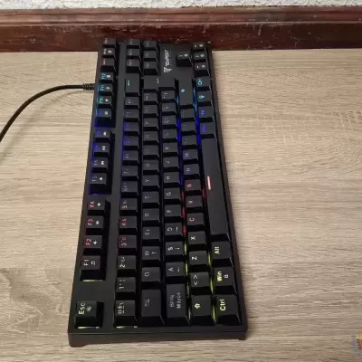 Teclado mecânico preto com iluminação RGB sobre mesa de madeira