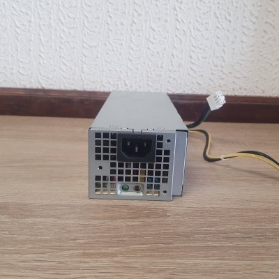 Fonte de alimentação para computador metálica prateada com cabos e conectores sobre chão de madeira clara