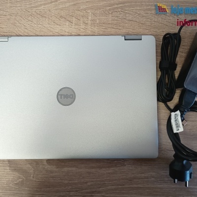 Portátil Dell prateado com carregador preto em mesa de madeira
