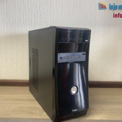 Computador de secretária preto NOX sobre superfície de madeira clara com texto de loja informática na parede atrás