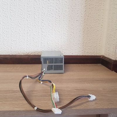 Fonte de alimentação de computador com cabos coloridos numa mesa de madeira