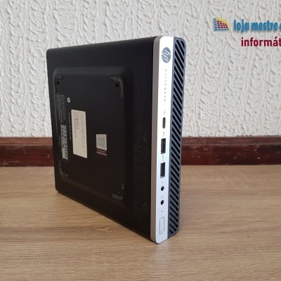 Mini PC preto com frente branca junto a parede branca texturizada