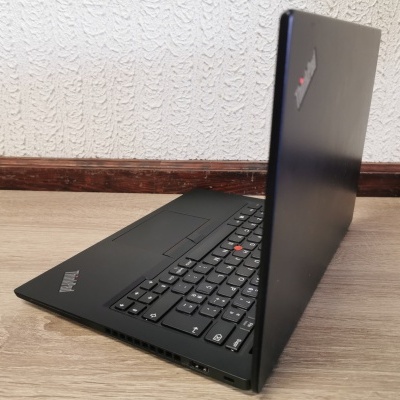 Computador portátil preto ThinkPad parcialmente aberto sobre mesa de madeira