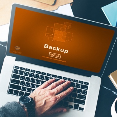 Computador portátil com ecrã de backup e mão sobre o teclado numa mesa com objetos