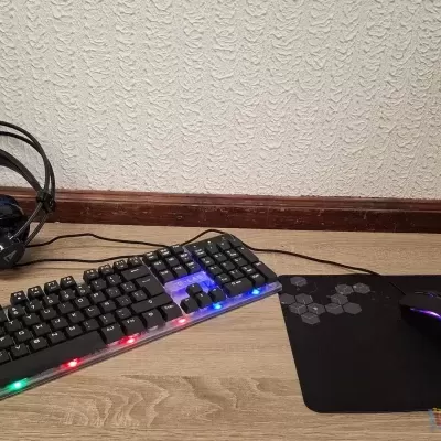 Teclado mecânico RGB, rato gaming, auscultadores e tapete sobre mesa de madeira