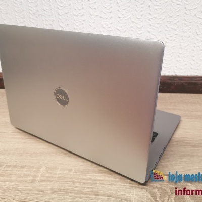 Portátil Dell prateado aberto numa mesa de madeira