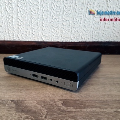 Computador compacto HP EliteDesk sobre mesa de madeira com parede branca ao fundo