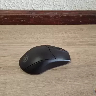 Rato informático sem fios preto numa superfície de madeira clara