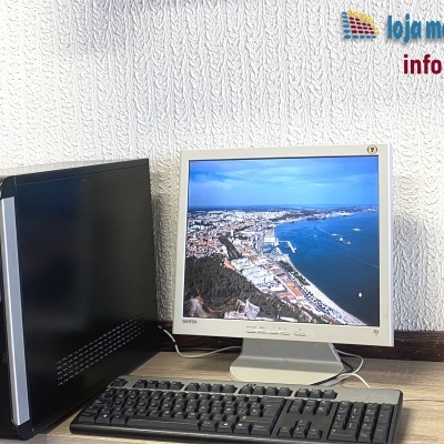 Computador desktop com monitor CRT e periféricos numa secretária