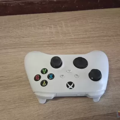 Comando Xbox branco com botões coloridos sobre mesa de madeira