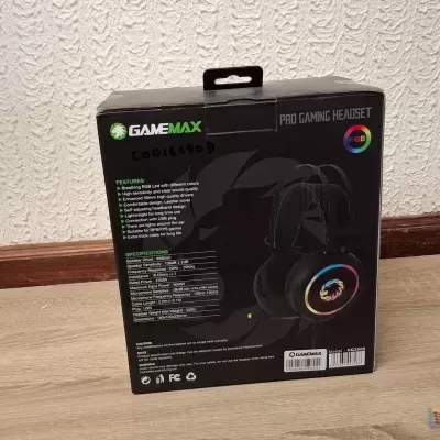 Caixa de headset Game Max em chão de madeira contra parede branca texturada