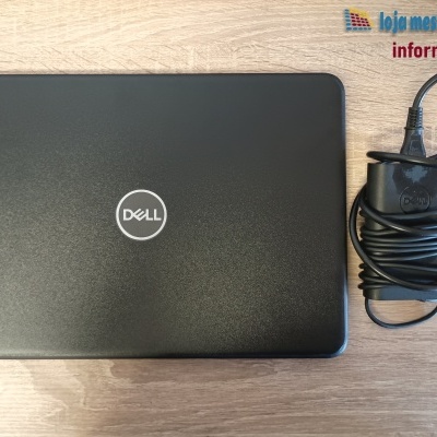 Computador portátil preto Dell com carregador sobre mesa de madeira clara