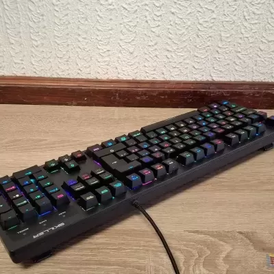 Teclado mecânico preto com iluminação RGB no chão de madeira clara