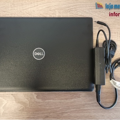 Computador portátil Dell preto com carregador numa mesa de madeira clara