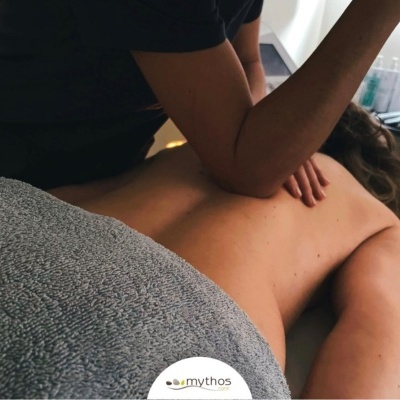 Pessoa a receber massagem nas costas com toalha cinza e massagista