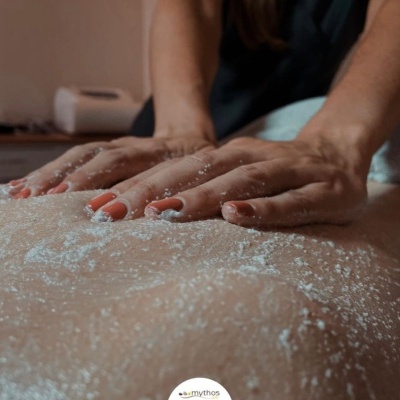 Mãos aplicando pó branco granular numa massagem