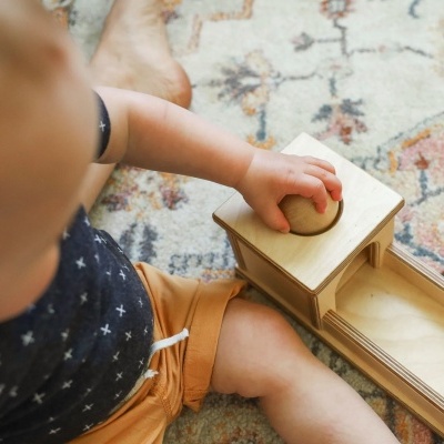 Criança a brincar com brinquedo de madeira sobre tapete colorido