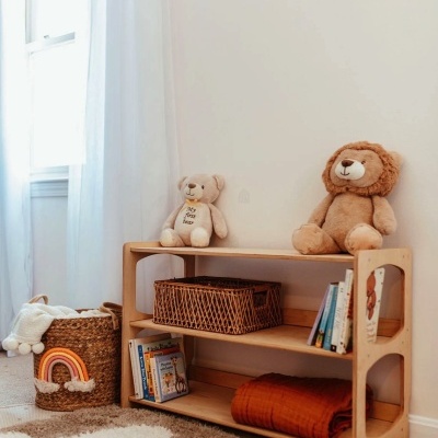Estante de madeira com peluches, livros e cesta em quarto infantil