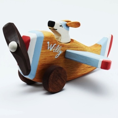 Avião de madeira pintado com hélice castanha e cão na cabine