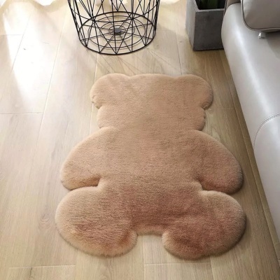Tapete felpudo em forma de urso bege claro junto a sofá e cesta metálica
