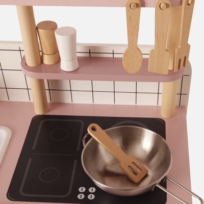 Cozinha de brincar cor-de-rosa com panela de metal, utensílios de madeira e placa de fogão preta