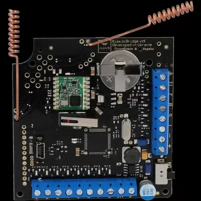 Placa eletrónica preta com terminais azuis e antenas de cobre espiral