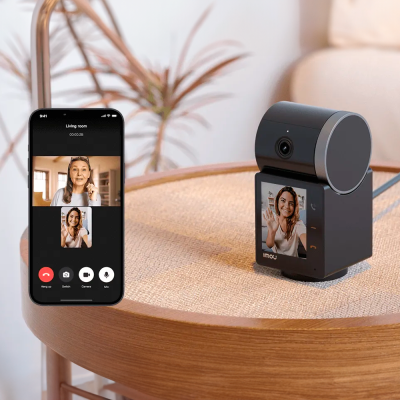 Câmara de vigilância e smartphone com videochamada numa mesa redonda de madeira