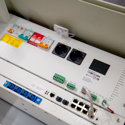 Painel elétrico branco com disjuntores coloridos, tomadas, conectores e portas Ethernet