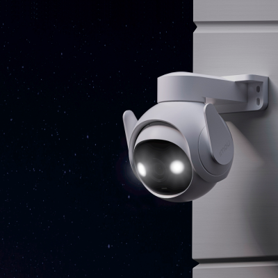 Câmara de segurança branca em parede cinza, noite com céu estrelado