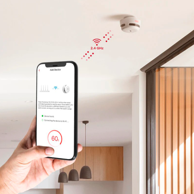 Detector de fumo branco no tecto com smartphone mostrando configuração Wi-Fi