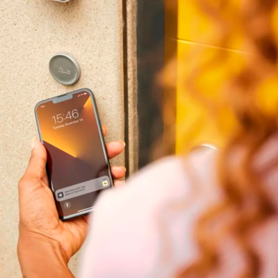 Pessoa a segurar smartphone perto de dispositivo Yale numa porta amarela