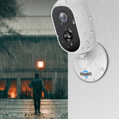 Câmara de vigilância exterior Hiseeu branca e preta em parede, com chuva e pessoa ao fundo