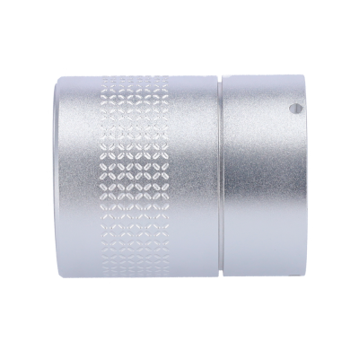 Objeto metálico cilíndrico prateado com textura geométrica gravada