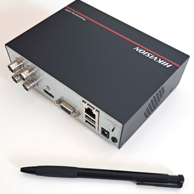 Aparelho Hikvision preto com várias portas conectado e caneta preta sobre superfície branca