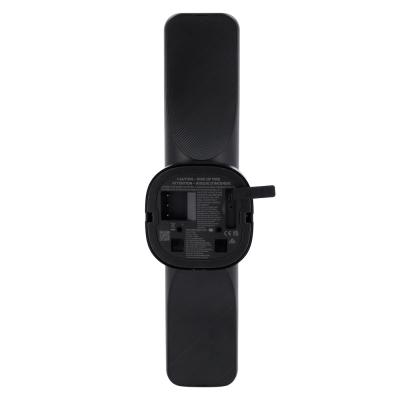 Controlo remoto preto com tampa da pilha aberta e texto de advertência