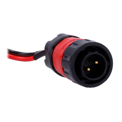 Conector elétrico redondo preto e vermelho com dois pinos dourados e fios ligados