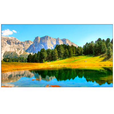 Paisagem natural com montanhas, árvores, campo de relva e lago refletindo o céu
