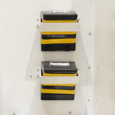 Duas caixas retangulares pretas com faixas amarelas montadas numa parede branca