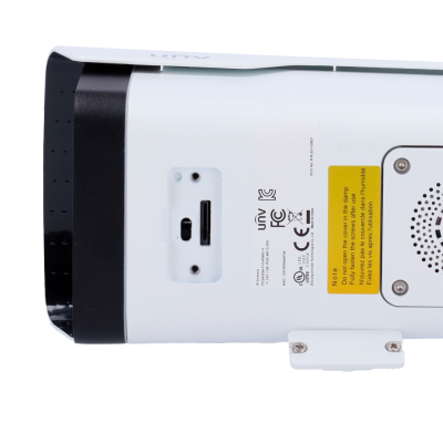 Câmara de segurança branca e preta com etiquetas técnicas e instruções amarelas.