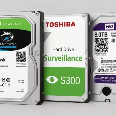 Três discos rígidos 8TB SEAGATE, TOSHIBA e WD com etiquetas coloridas num fundo cinzento