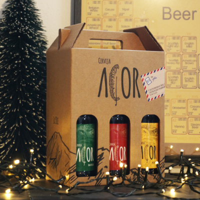 Pack de três garrafas de cerveja CERVEJA ACOR em caixa de cartão com rótulos coloridos e decoração festiva.