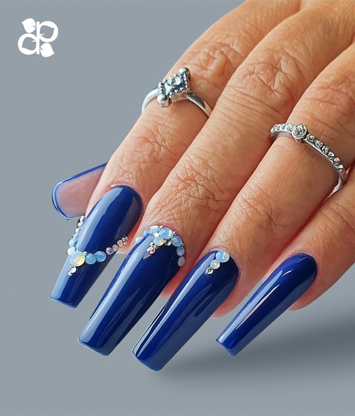 Unha postiça azul escuro com cristais e argolas