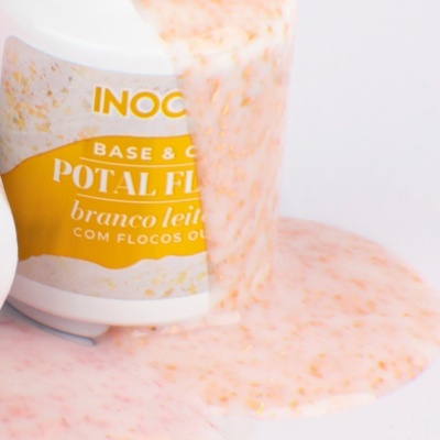 Frasco com rótulo amarelo e branco e produto creme com flocos laranja-rosados a escorrer.