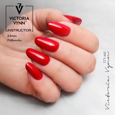 Mão com unhas vermelhas brilhantes e texto promocional Victoria Vynn.
