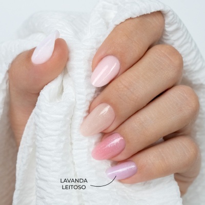 Unhas com esmalte em tons pastel seguras por tecido branco