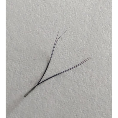 Componente eletrônico fino metálico com três filamentos sobre superfície branca