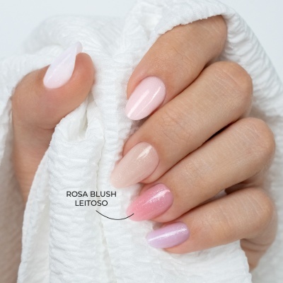 Unhas pintadas em tons pastel rosa segurando tecido branco.