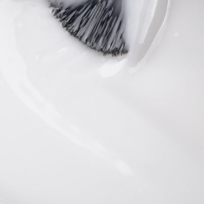 Pincel preto com esmalte branco aplicado numa superfície branca