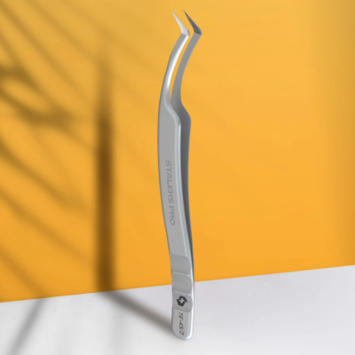 Pinça metálica curva STALEKS PRO PTF-42 sobre superfície branca e fundo laranja